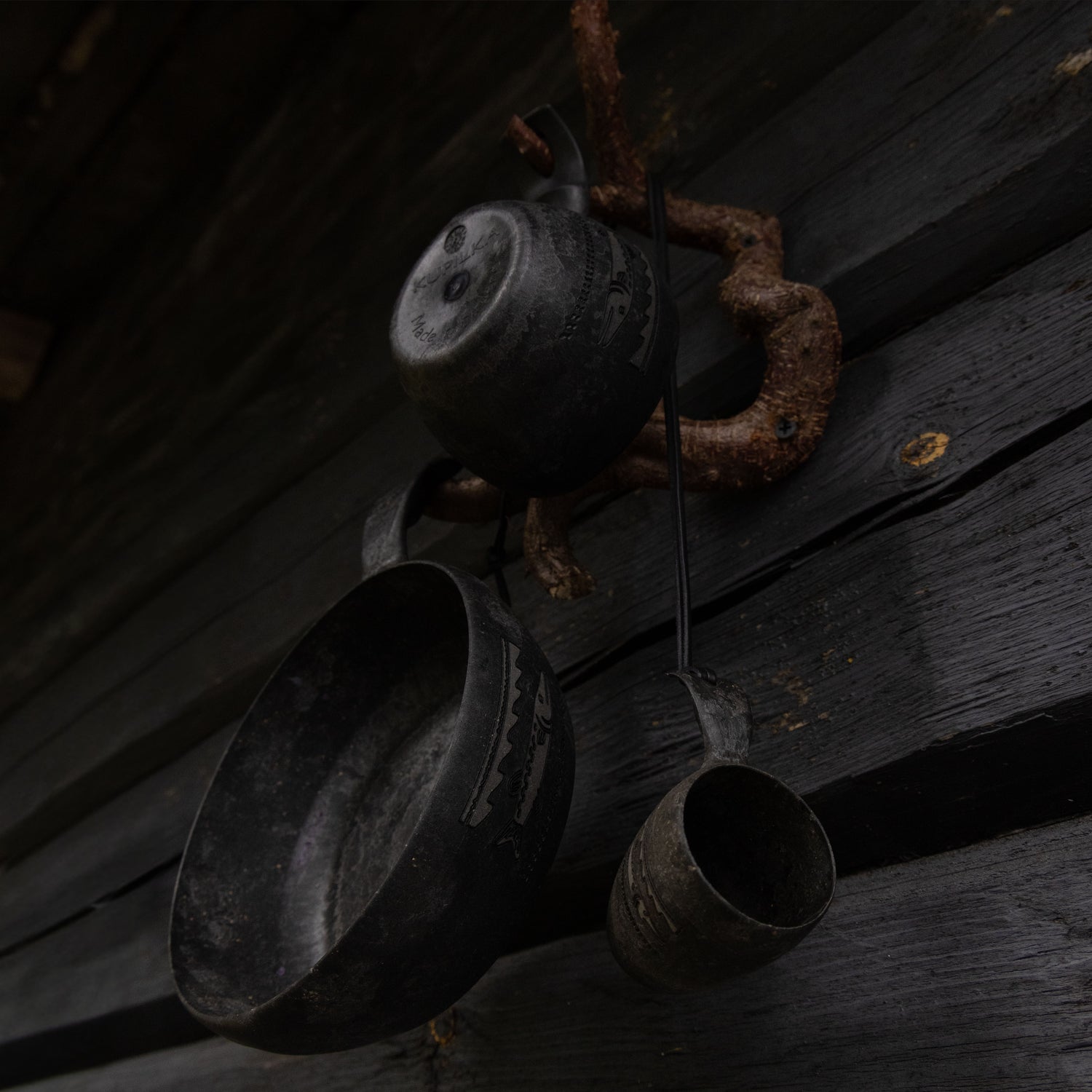 Mustat Kupilka retkiastiat roikkuvat naulakossa, kyljessä Kalevala Hauki kaiverrukset