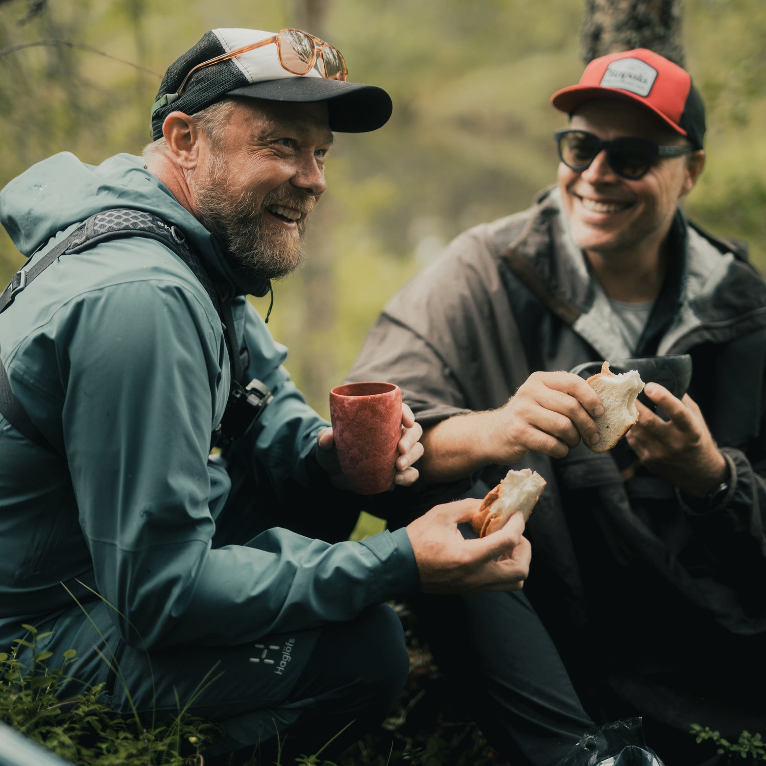 two men having bread and holding cup in forest